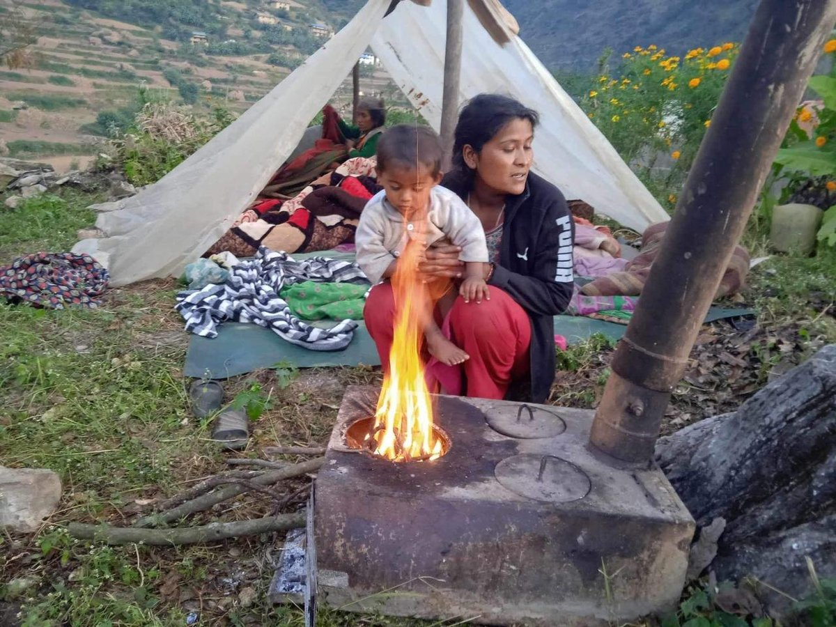 Madre e hijo junto al fuego en un campamento tras las inundaciones, Nepal
